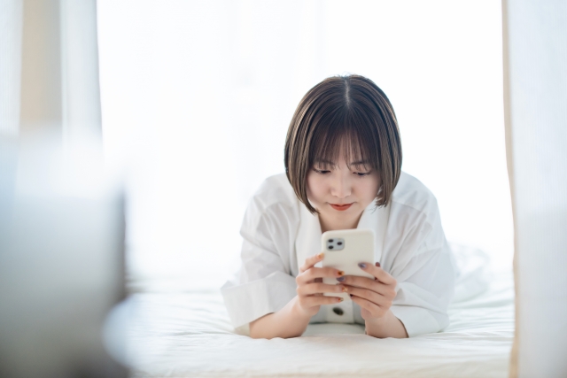 寝転んでスマホを見る女の子